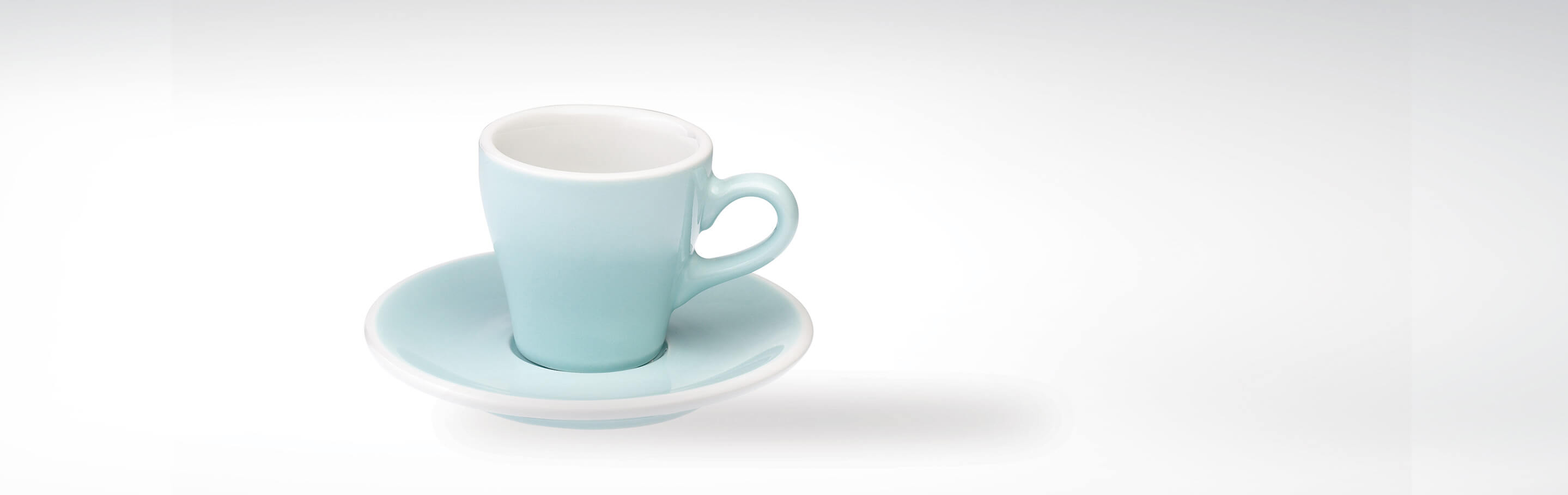 Türkisblaue Espressotasse mit Untertasse aus Keramik vor weißem Hintergrund